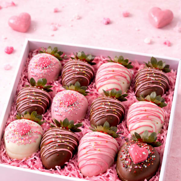 Box of chocolate-covered strawberries with pink and white drizzle