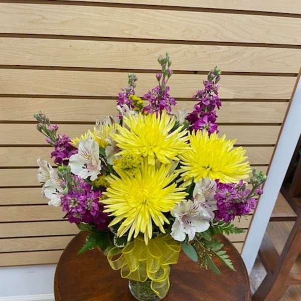 Bouquet of yellow chrysanthemums and purple flowers in a glass vase