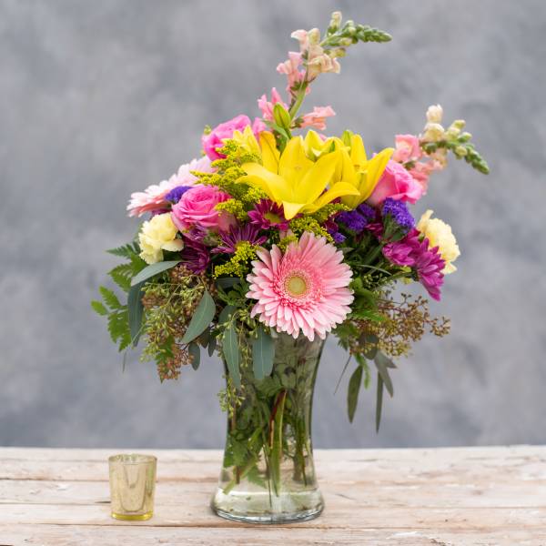Mixed bouquet in a glass vase with pink, yellow, and purple flowers