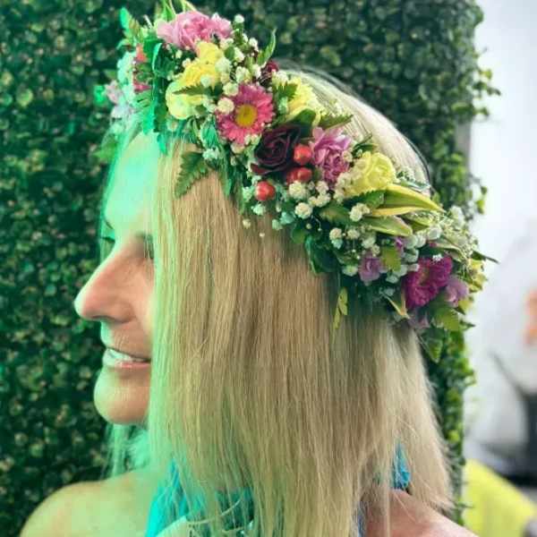 Woman wearing a floral crown with pink, yellow, and purple flowers