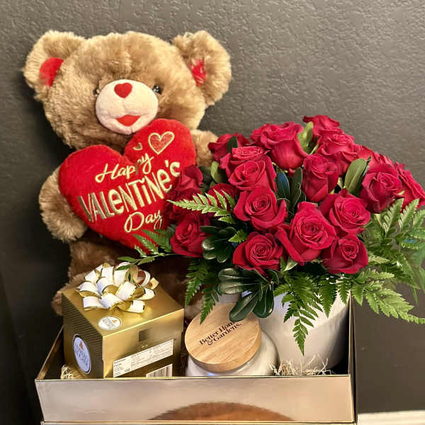 Teddy bear with a Valentine heart beside red roses and a gift box