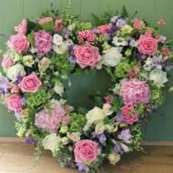 Heart-shaped wreath of pink and white flowers with touches of lavender.