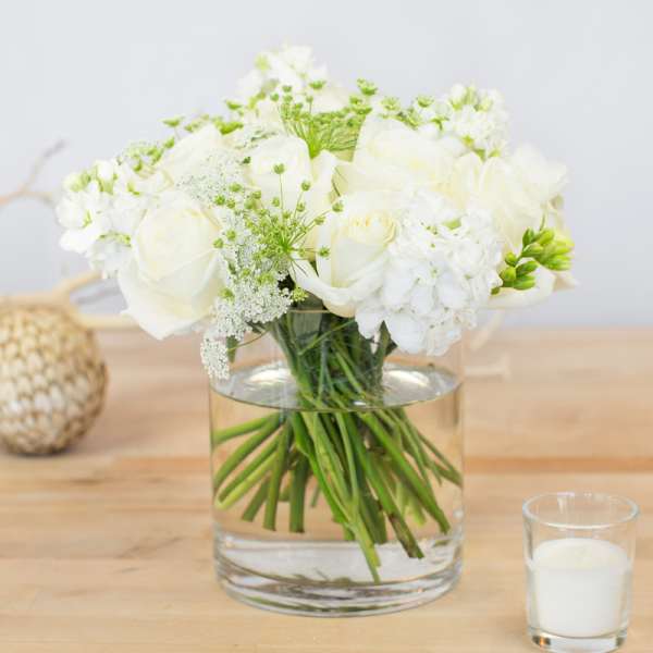 White roses and white blooms in a clear glass vase