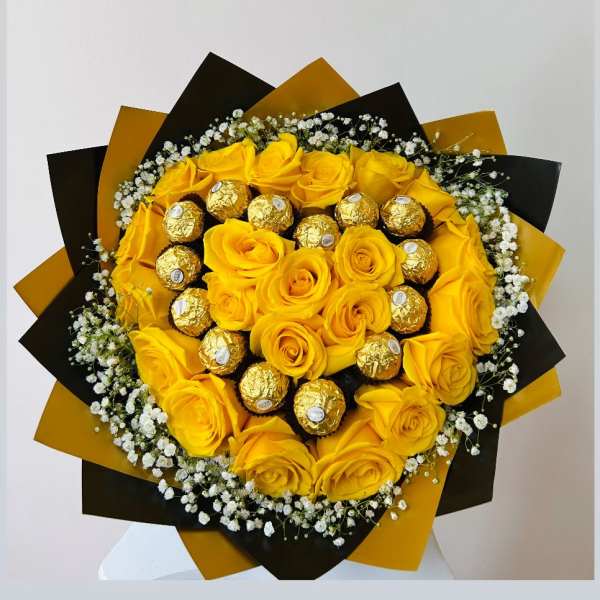Yellow roses with gold-wrapped chocolates in a black and gold bouquet