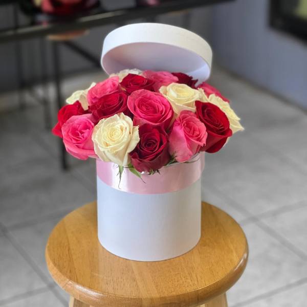 Pink, red, and white roses arranged in a round hat box