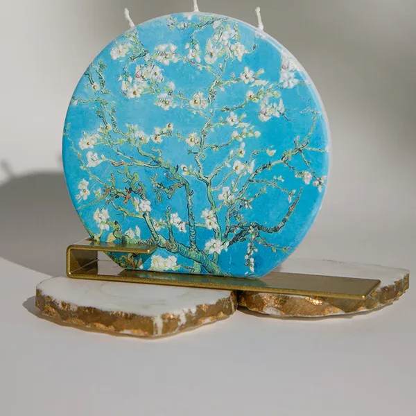 Round blue decorative candle with white blossoms on a gold stand