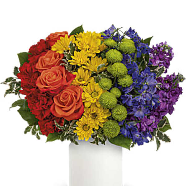 Colorful bouquet of roses, daisies, and pompons in a white vase