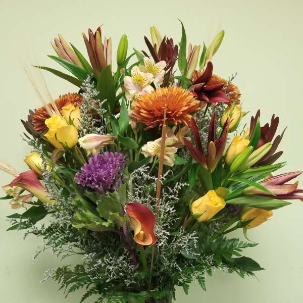 Mixed bouquet of lilies, roses, calla lilies, and chrysanthemums in a glass vase