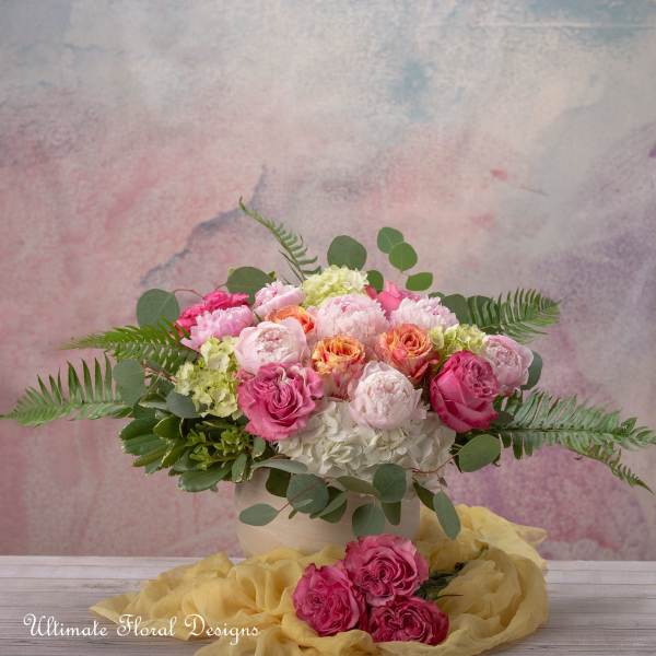 Pink and peach rose bouquet in a white vase with greenery