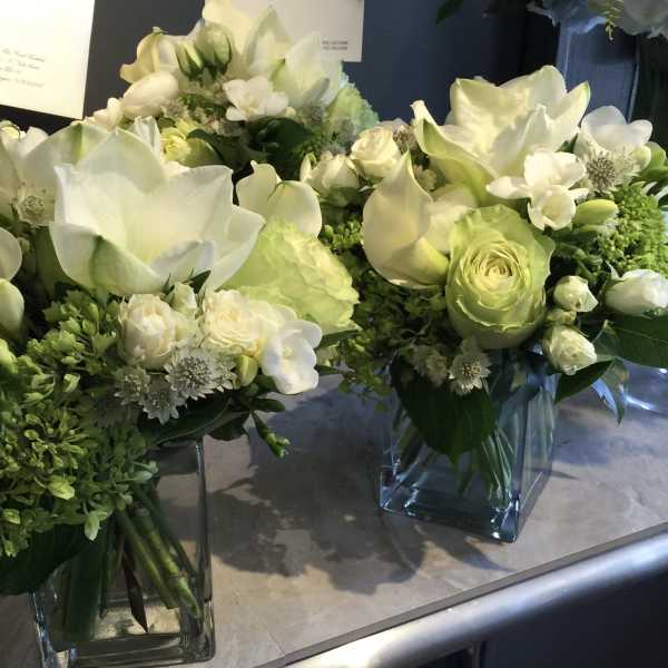 White and pale green floral arrangements in square glass vases