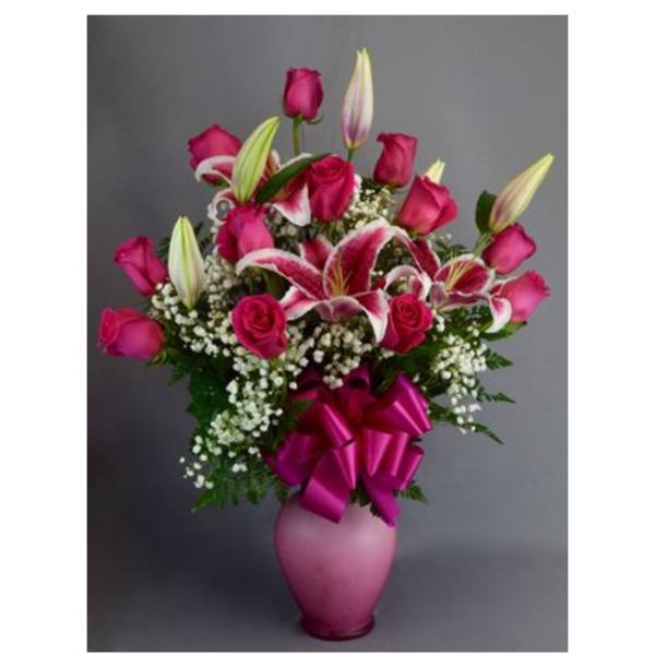 Pink roses and lilies in a pink vase with a ribbon