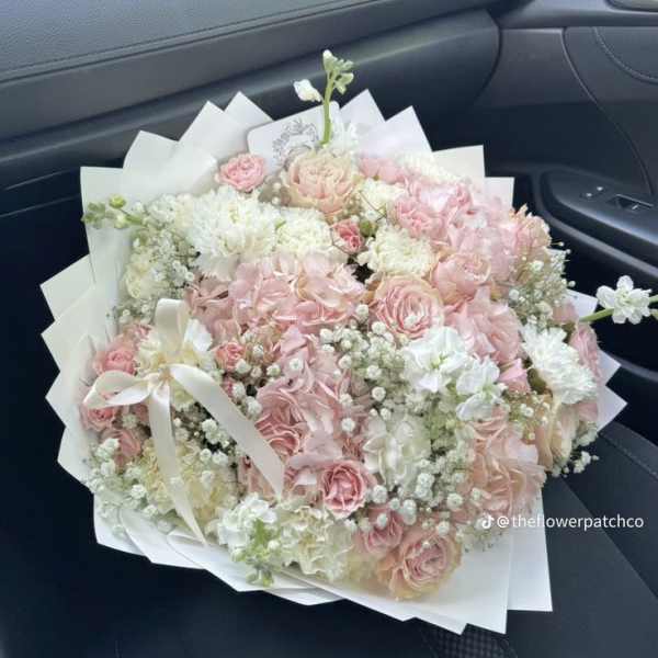 Large bouquet of pink and white flowers wrapped in white paper