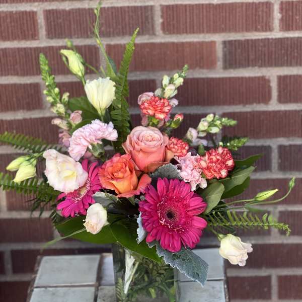 Mixed pink and peach bouquet in a square glass vase