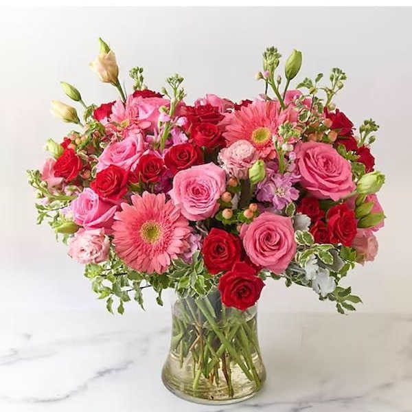 Pink and red rose bouquet with gerbera daisies in a glass vase