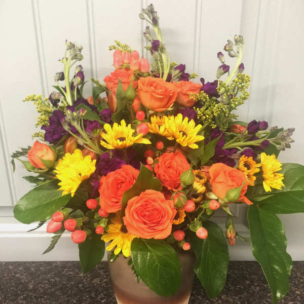 Orange roses and yellow daisies in a ceramic vase