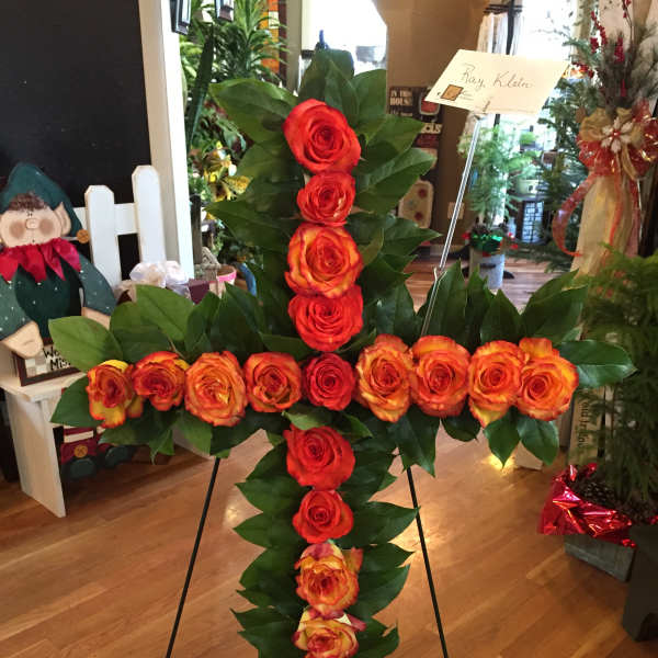 Cross-shaped rose arrangement on a stand with red and orange roses
