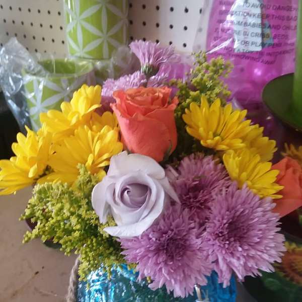 Mixed bouquet with roses and daisies in a blue glass vase