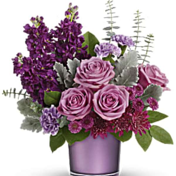 Purple roses and mixed blooms in a lavender glass vase