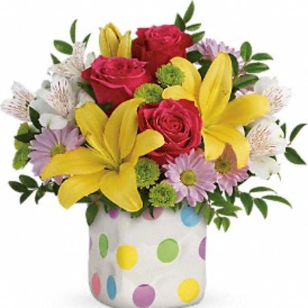 Bouquet of roses, lilies, and daisies in a polka-dot vase
