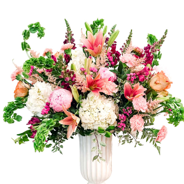 Large mixed flower arrangement in a white pedestal vase