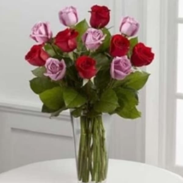 Bouquet of red and lavender roses in a clear glass vase
