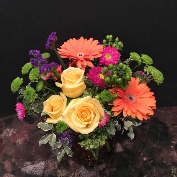Bouquet of yellow roses, orange gerbera daisies, and purple accents