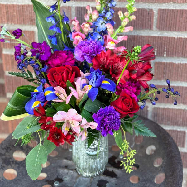 Colorful mixed bouquet with roses, irises, and alstroemeria in a glass vase