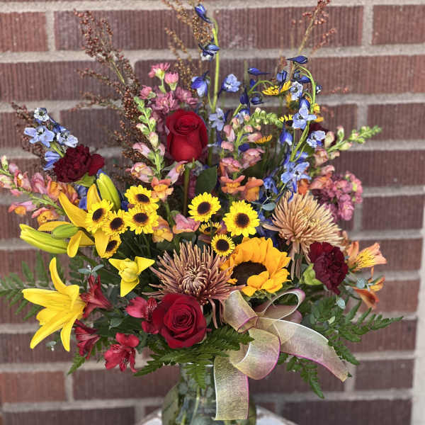 Mixed bouquet in a glass vase with red roses and yellow sunflowers