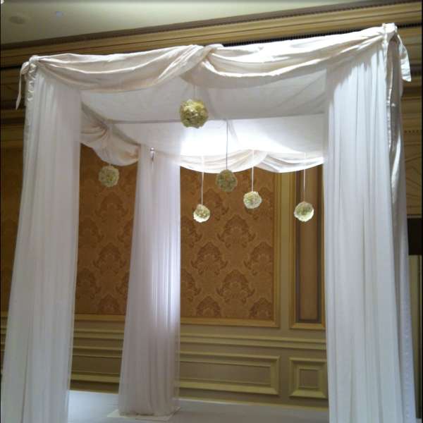 White draped wedding canopy with hanging floral pomanders