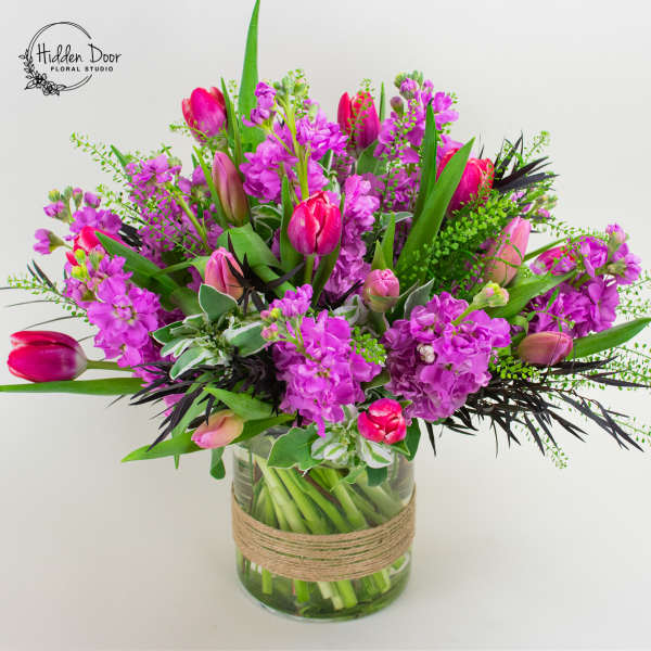 Pink tulips and purple flowers in a glass vase with twine wrap