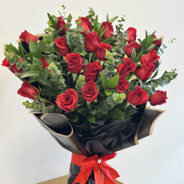 Bouquet of red roses wrapped in black paper with a red ribbon