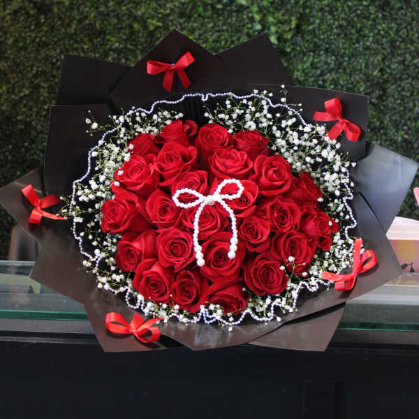 Bouquet of red roses with baby's breath and black wrapping