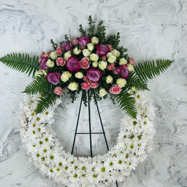 Standing floral wreath with pink and white roses and white daisies on an easel