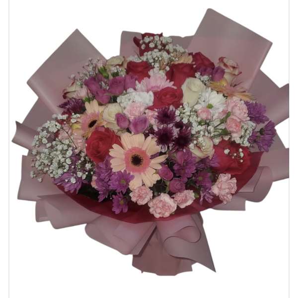 Mixed bouquet of pink, purple, and white flowers wrapped in pink paper
