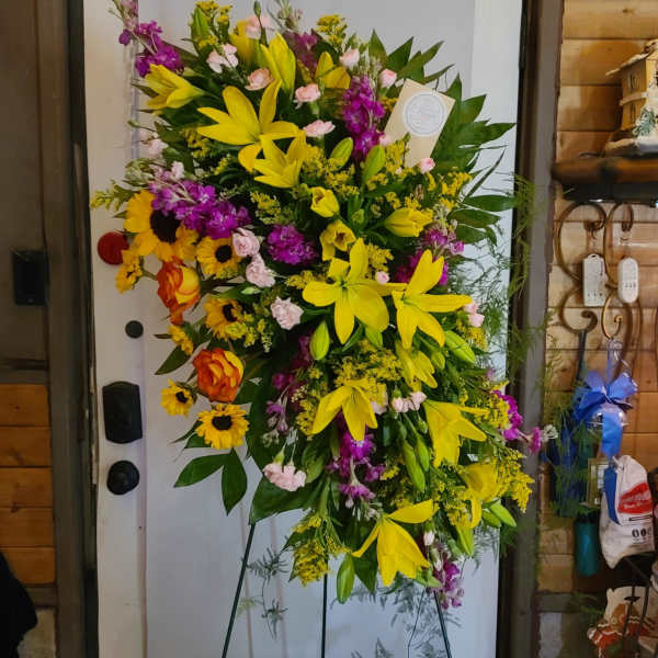 Large standing floral spray with yellow lilies and purple flowers