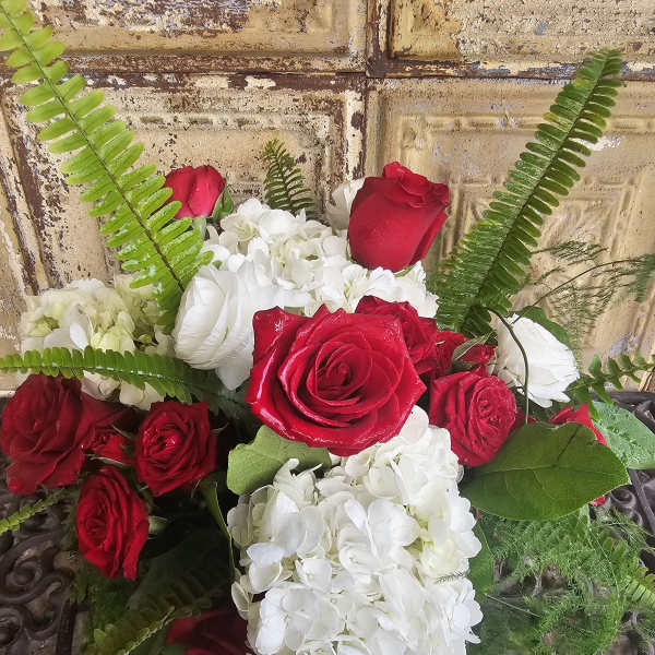 Red roses and white hydrangeas arranged with fern fronds