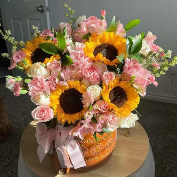 Bouquet of sunflowers, pink roses, and pink alstroemeria in an orange vase