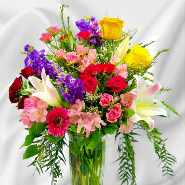 Mixed bouquet of roses, lilies, and pink flowers in a glass vase