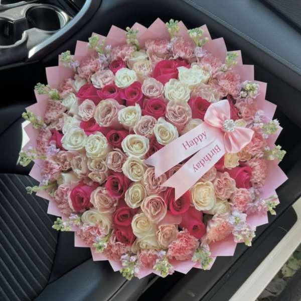 Pink and white rose bouquet with carnations and a birthday ribbon