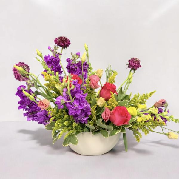 Colorful mixed flower arrangement in a white bowl vase
