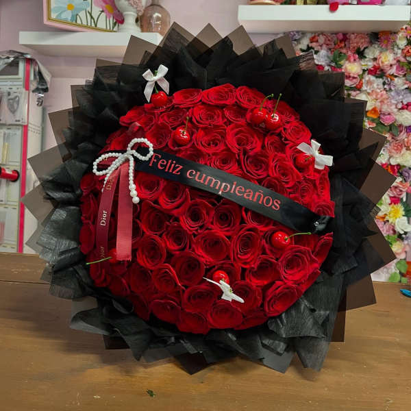 Large bouquet of red roses wrapped in black paper with a birthday ribbon