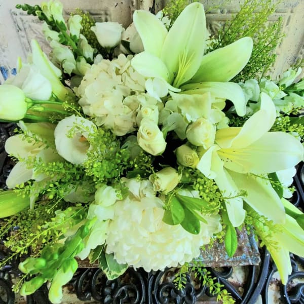 White lilies and roses arranged with hydrangeas and greenery