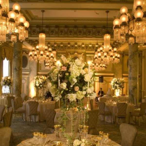 Elegant banquet hall with tall white floral centerpieces and gold table settings