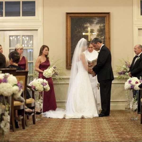 Wedding ceremony with floral aisle arrangements and bridesmaids holding bouquets