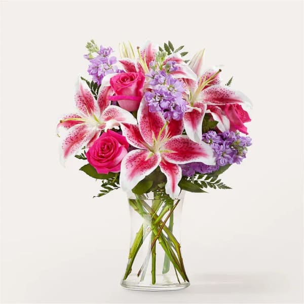 Pink roses and spotted lilies in a clear glass vase
