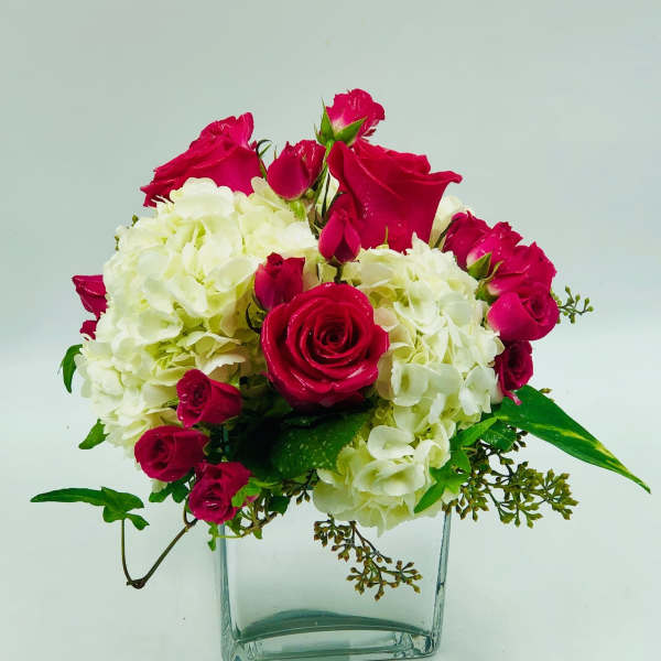 Pink roses and white hydrangeas arranged in a clear glass vase