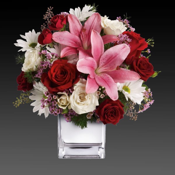 Pink lilies and red roses in a clear square vase