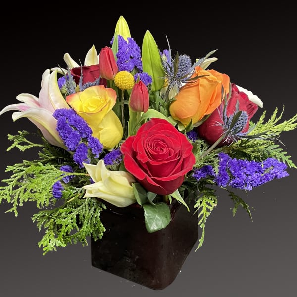 Mixed bouquet of roses and lilies in a dark vase