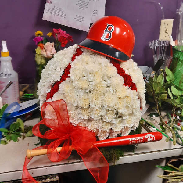 White floral arrangement with a red baseball helmet and bat