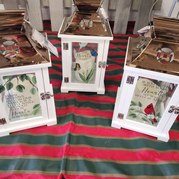 Three white lanterns with memorial messages and butterfly designs